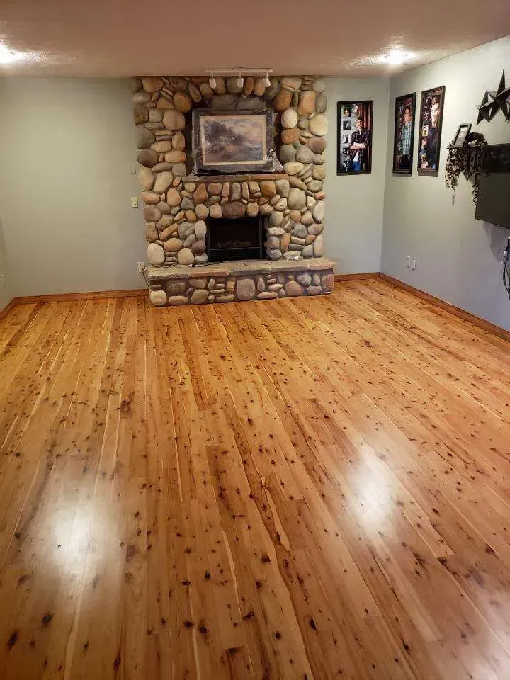 A living room with a wooden floor and a stone fireplace.