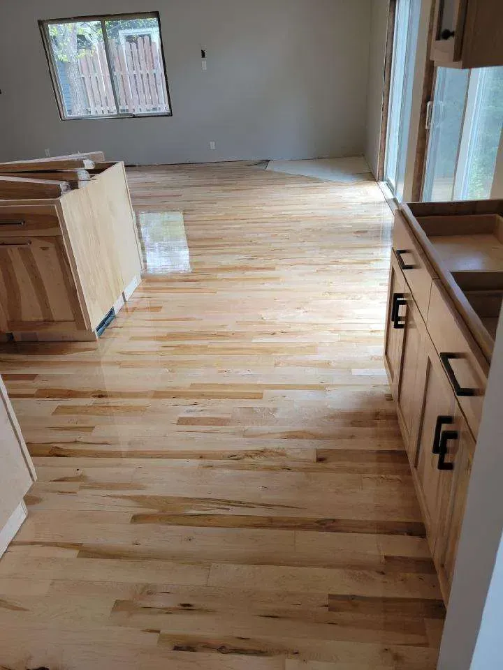 A kitchen with hardwood floors , cabinets , and a sink.