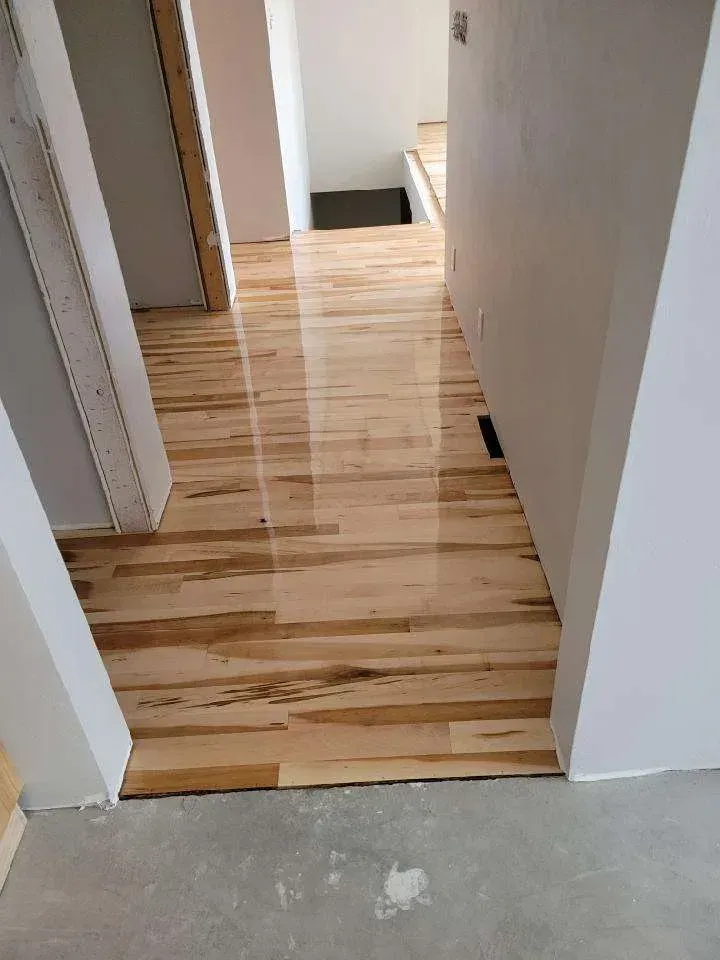 A hallway with hardwood floors in a house under construction.