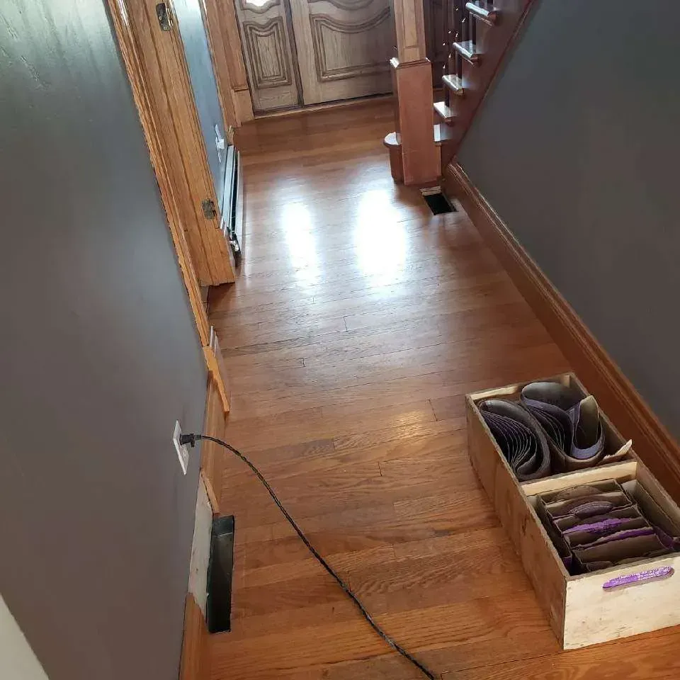 A wooden hallway with a box of shoes on the floor.