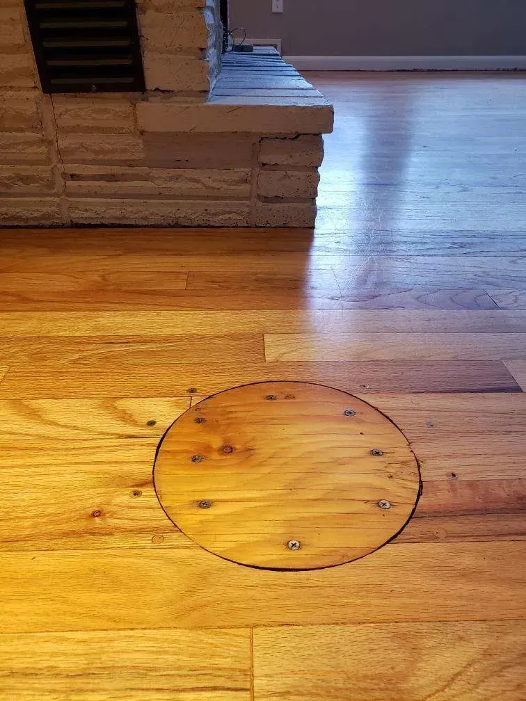 A wooden floor with a round hole in the middle of it.