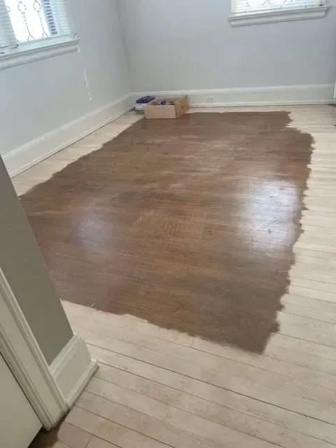 A wooden floor is being painted in a room.