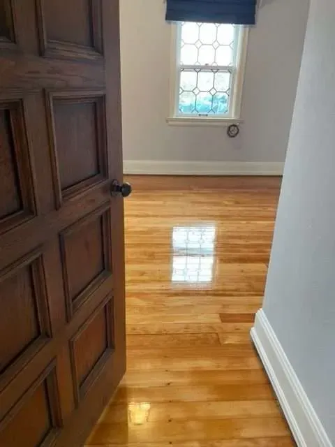 A door is open to a room with hardwood floors and a window.