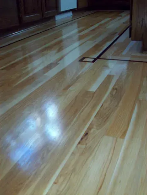 A close up of a wooden floor in a kitchen.