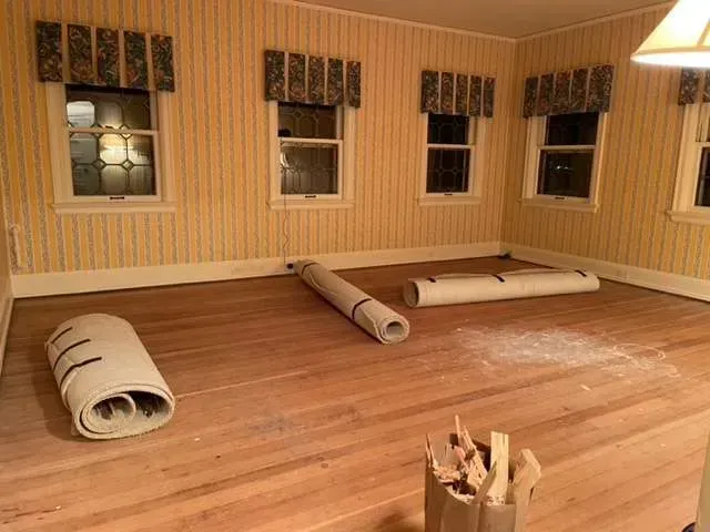 Three rolls of carpet are sitting on a wooden floor in a room.
