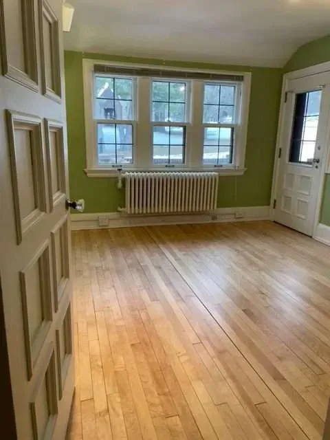 An empty living room with hardwood floors and green walls.