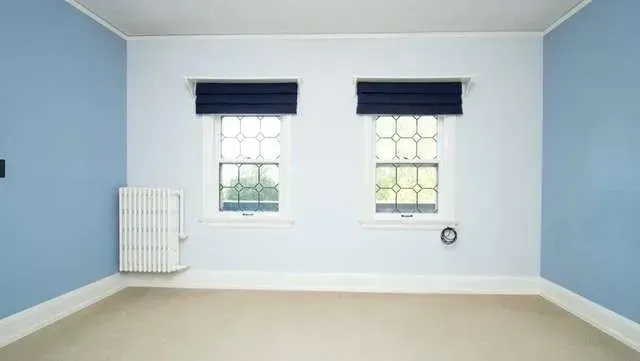 An empty room with blue walls and two windows