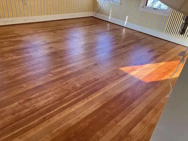 A room with a wooden floor and yellow striped wallpaper.