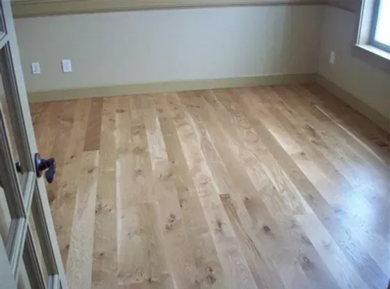 An empty room with hardwood floors and a window.