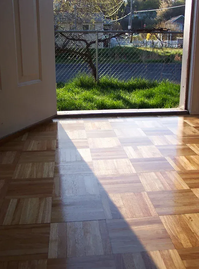 A wooden floor with a shadow of a door on it