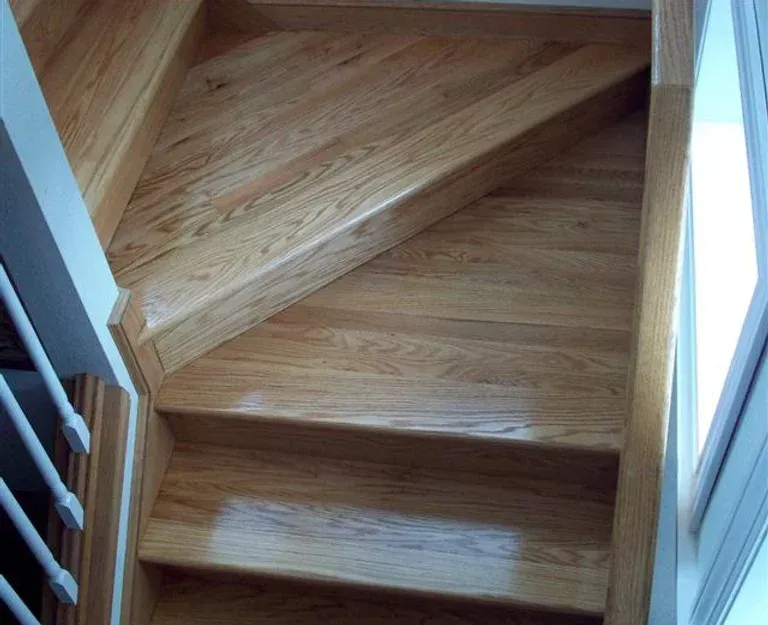 A wooden staircase with a white railing and a window