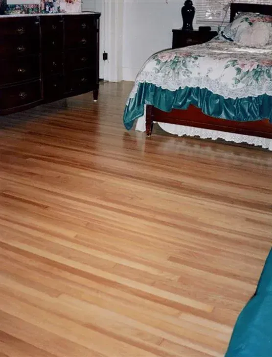 A bedroom with hardwood floors and a bed