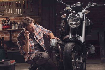 man on a call on his knee next to a bike in a garage