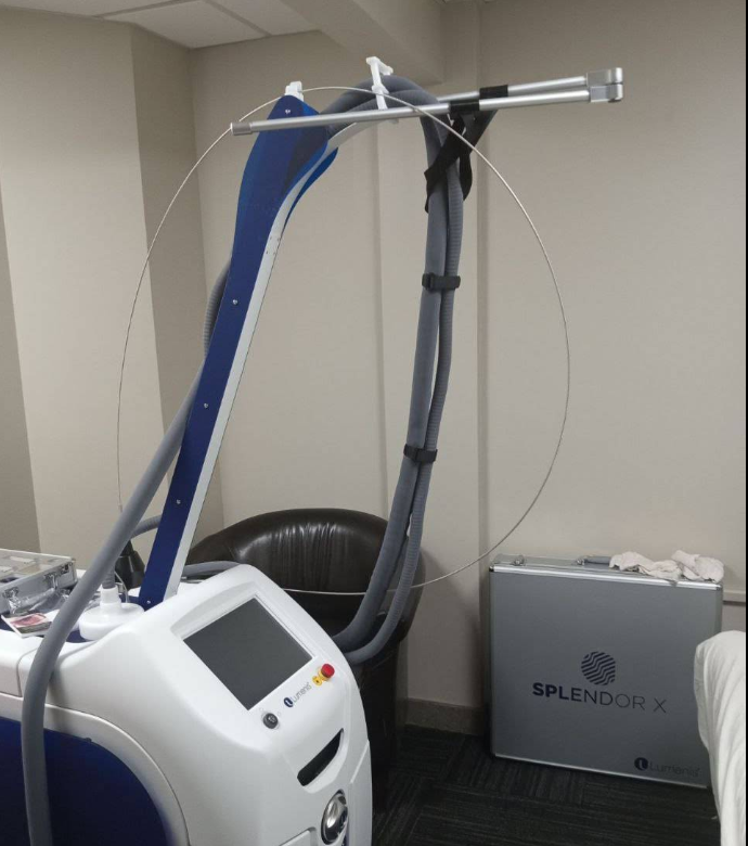 A blue and white Splendor X laser machine, with a gray tube and silver case, in a medical office setting.