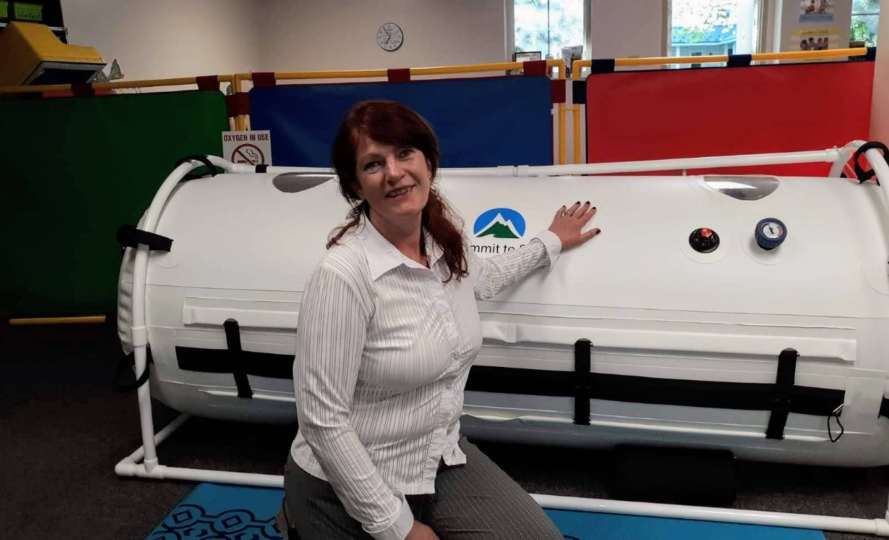 Person in pink gloves performing laser treatment on a leg.