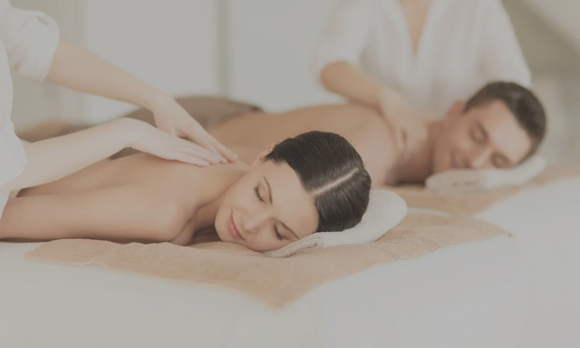 Couple receiving massage at a spa, lying face down with eyes closed.