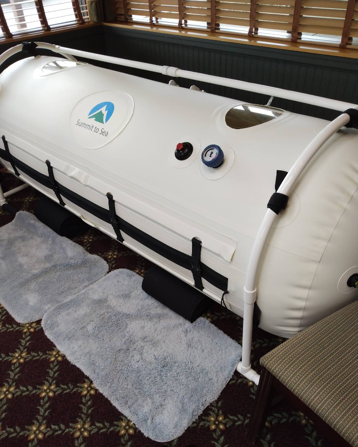 Woman receiving facial treatment; technician using a handheld device on her jawline.