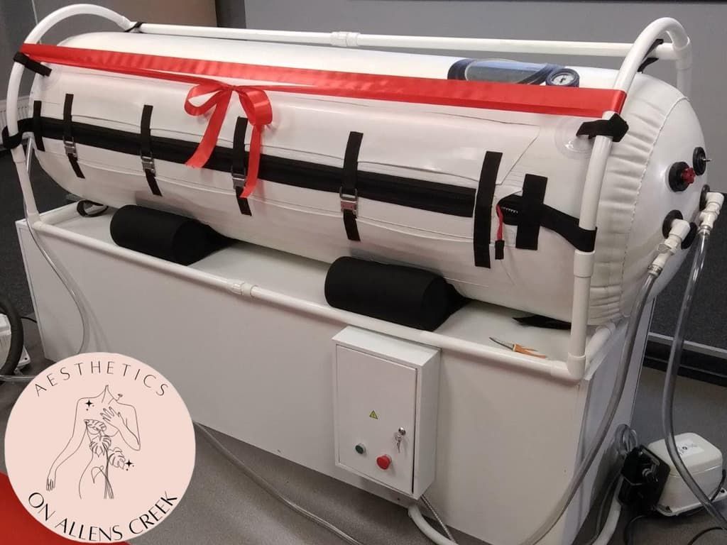 White hyperbaric chamber with red bow, black straps, on a white frame.