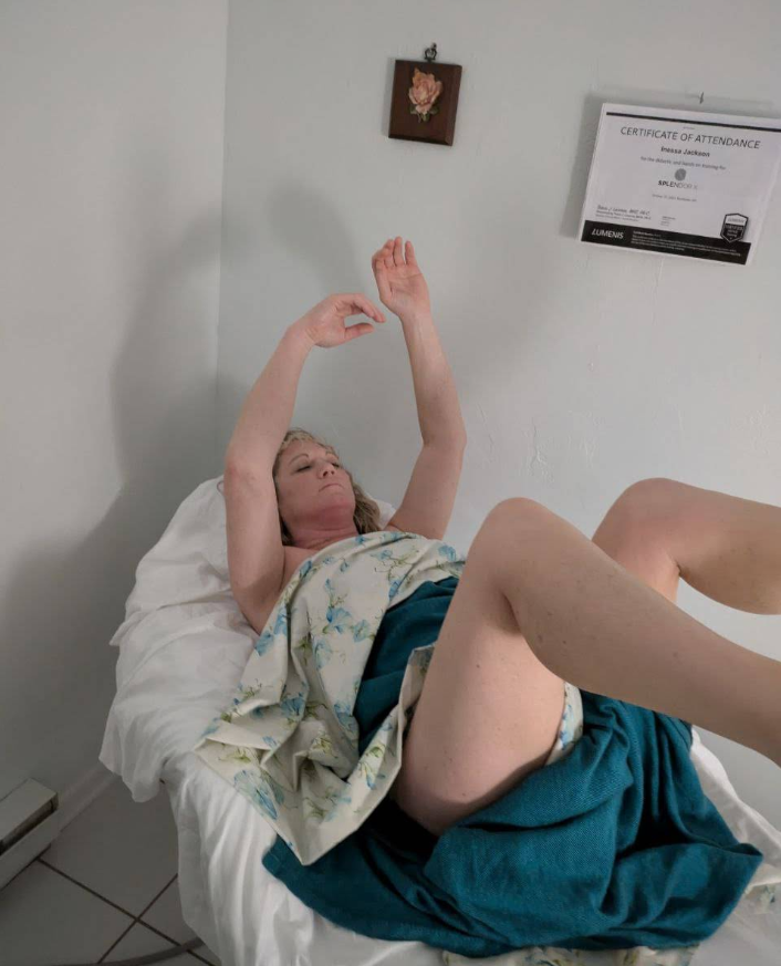 Woman lying on a bed with arms raised, covered by blue and floral blankets.