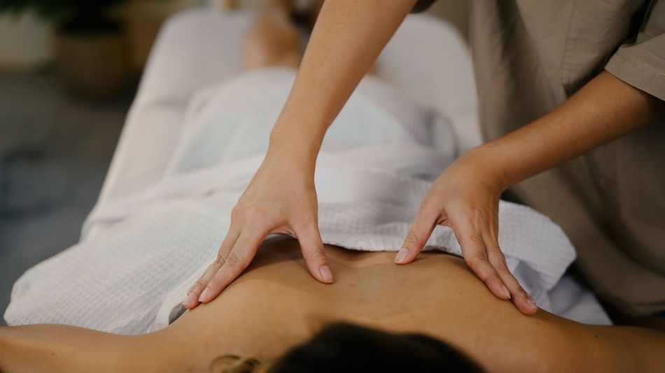Person receiving a back massage on a massage table. Hands of therapist on the back.
