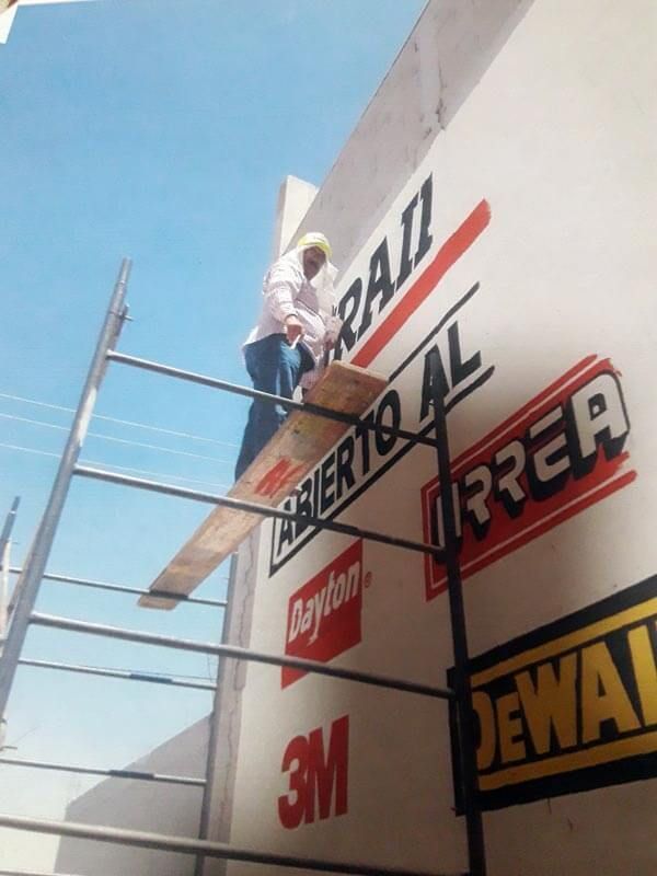 Un hombre en un andamio pinta un cartel que dice 3m.