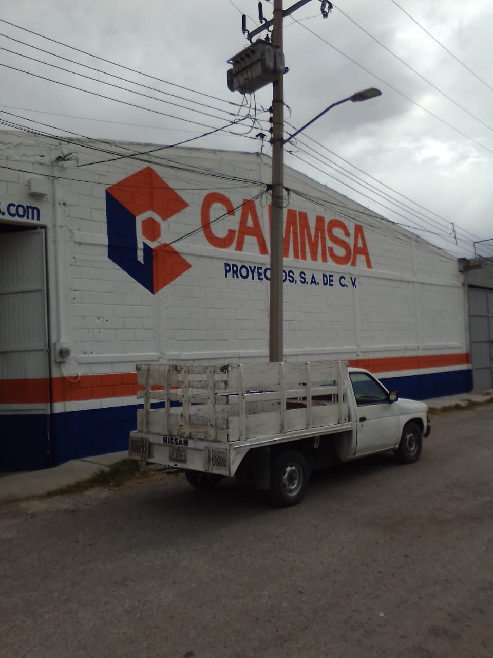 Un camión blanco está estacionado frente a un edificio que dice camisa