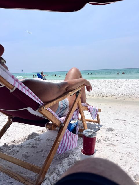 A woman is laying in a beach chair on the beach