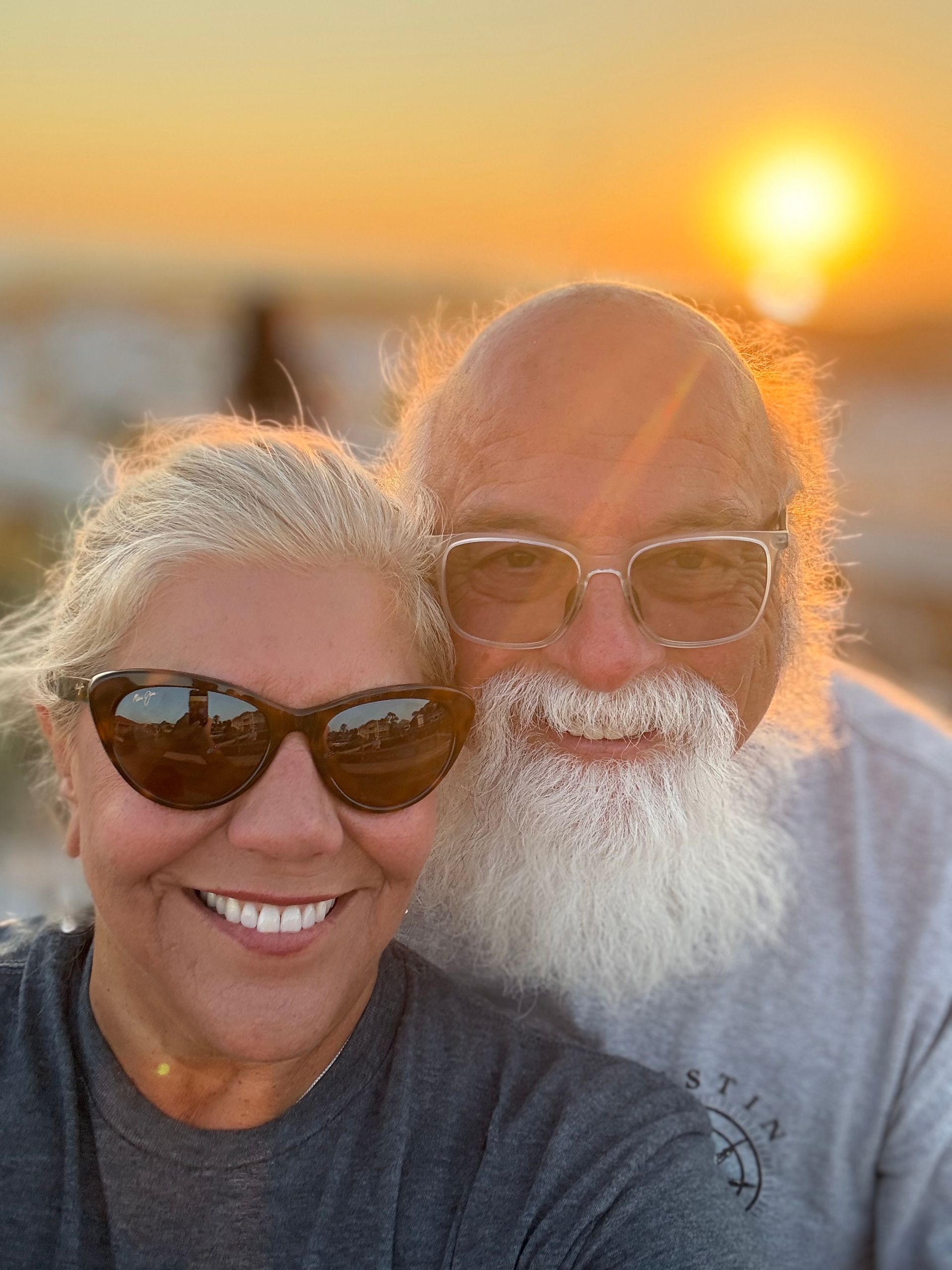 A man with a beard and a woman wearing sunglasses are posing for a picture.