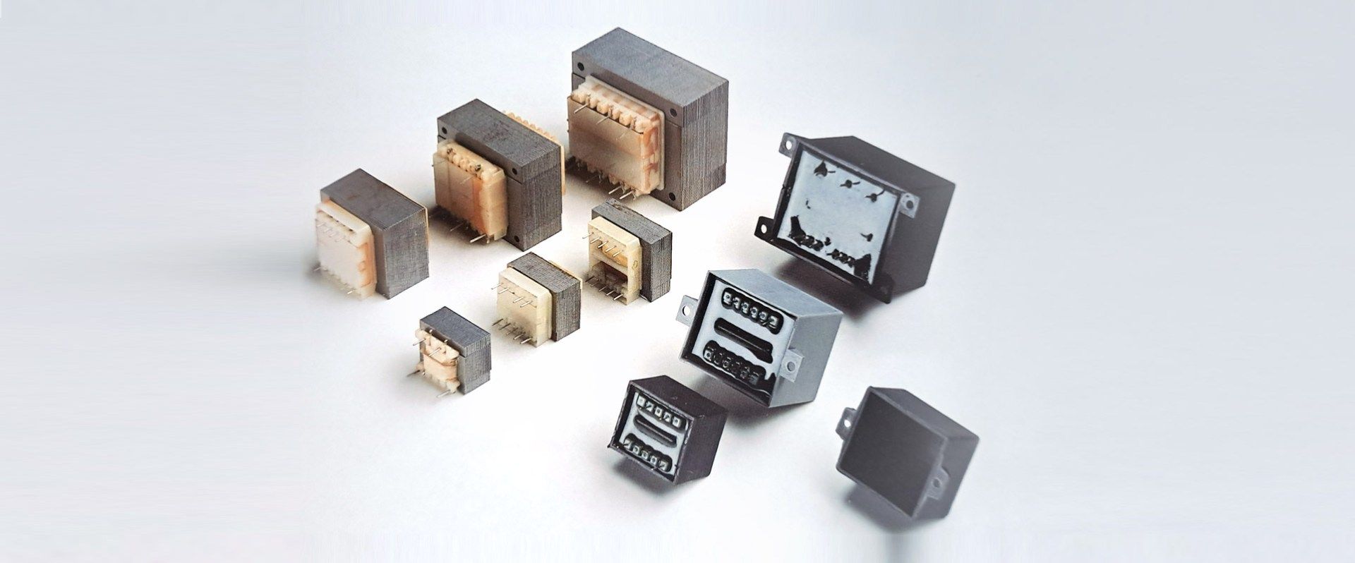 Raccolta di vari trasformatori elettronici su una superficie bianca.