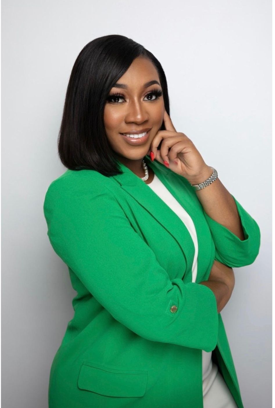 a woman in a green jacket is standing with her arms crossed and smiling .