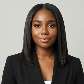 Portrait of a woman with dark hair in a black blazer against a light gray background