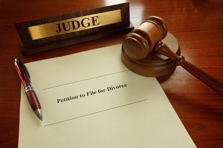 A judge 's gavel is sitting on top of a petition to file for divorce.