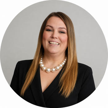 a woman wearing a pearl necklace and a black jacket is smiling.