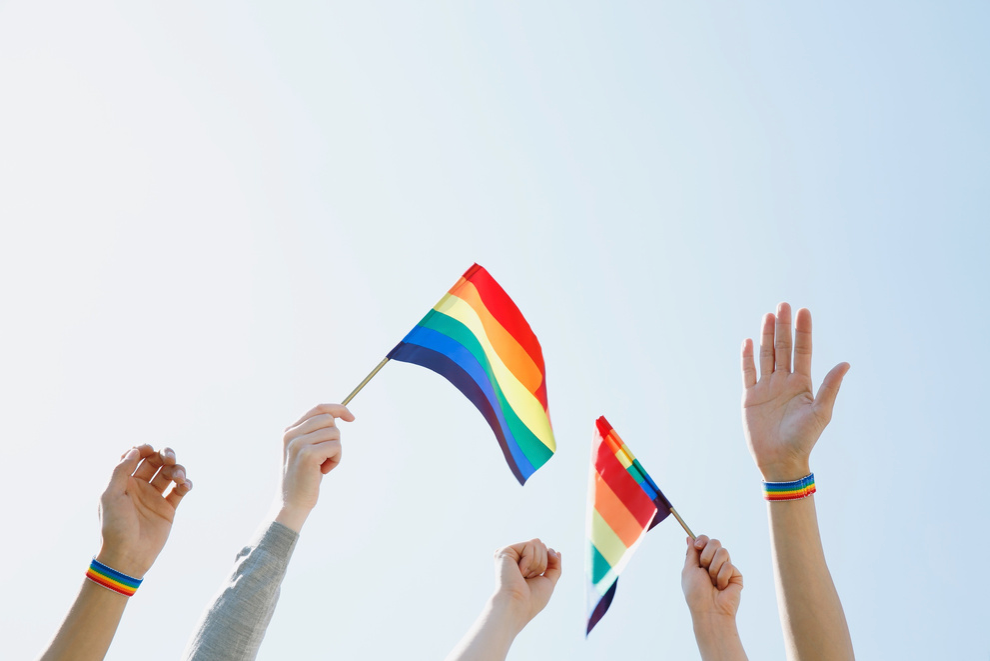 A group of people are holding rainbow flags in the air.