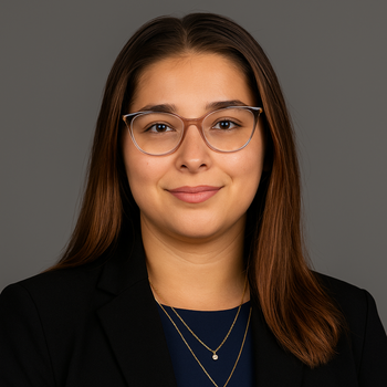a woman wearing a pearl necklace and a black jacket is smiling.