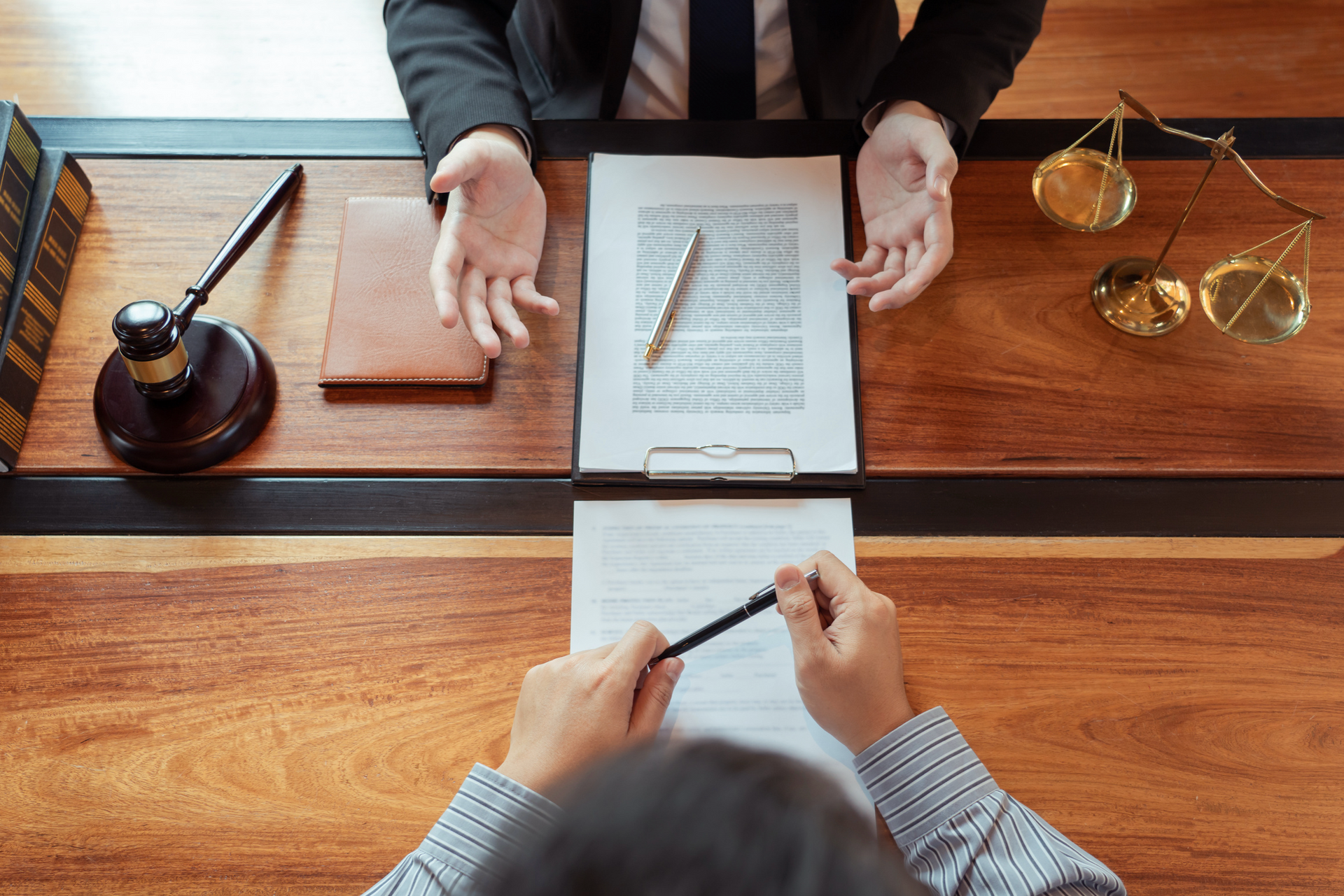 A man is sitting at a table with a lawyer and signing a document.