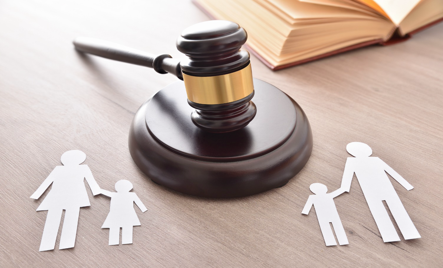 A judge 's gavel and paper cut outs of a family on a wooden table.