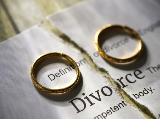 Two wedding rings are sitting on a piece of paper that says divorce