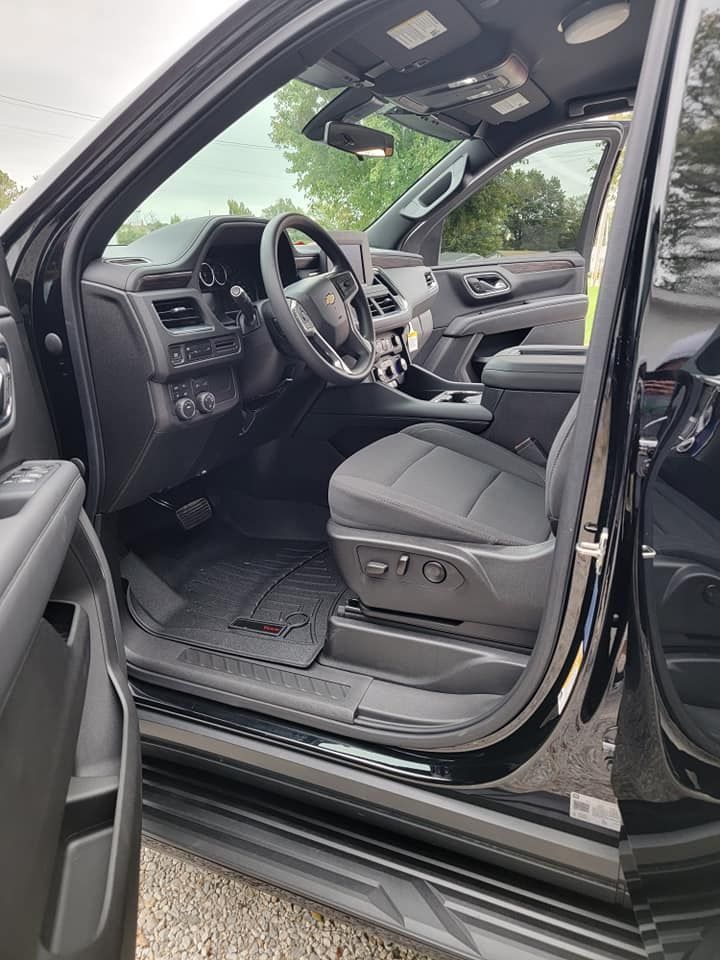 The inside of a black suv with the door open and the seats up.