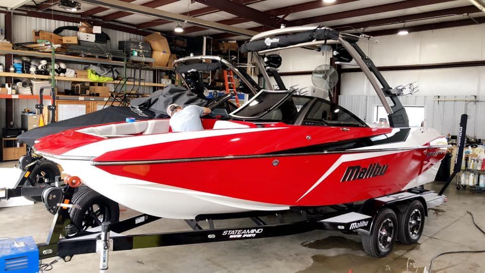 A red and white boat is parked in a garage.