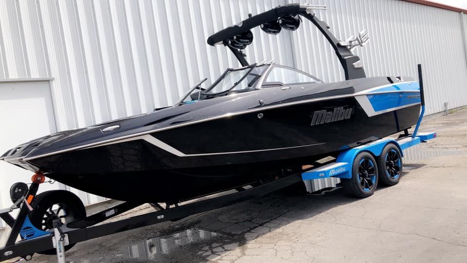 A black and blue boat is parked on a trailer in front of a building.