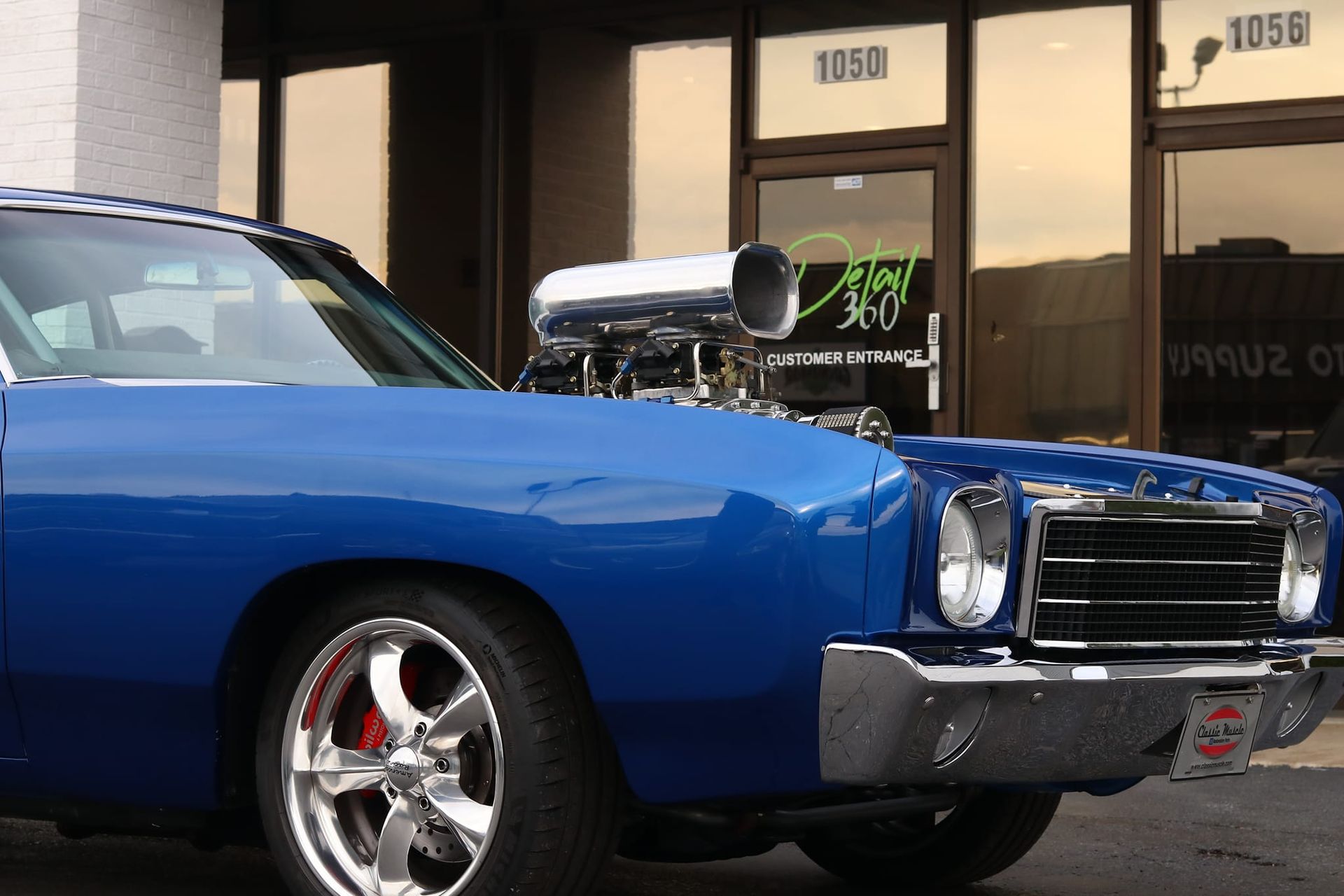 A blue car is parked in front of a building with the number 1050 on it
