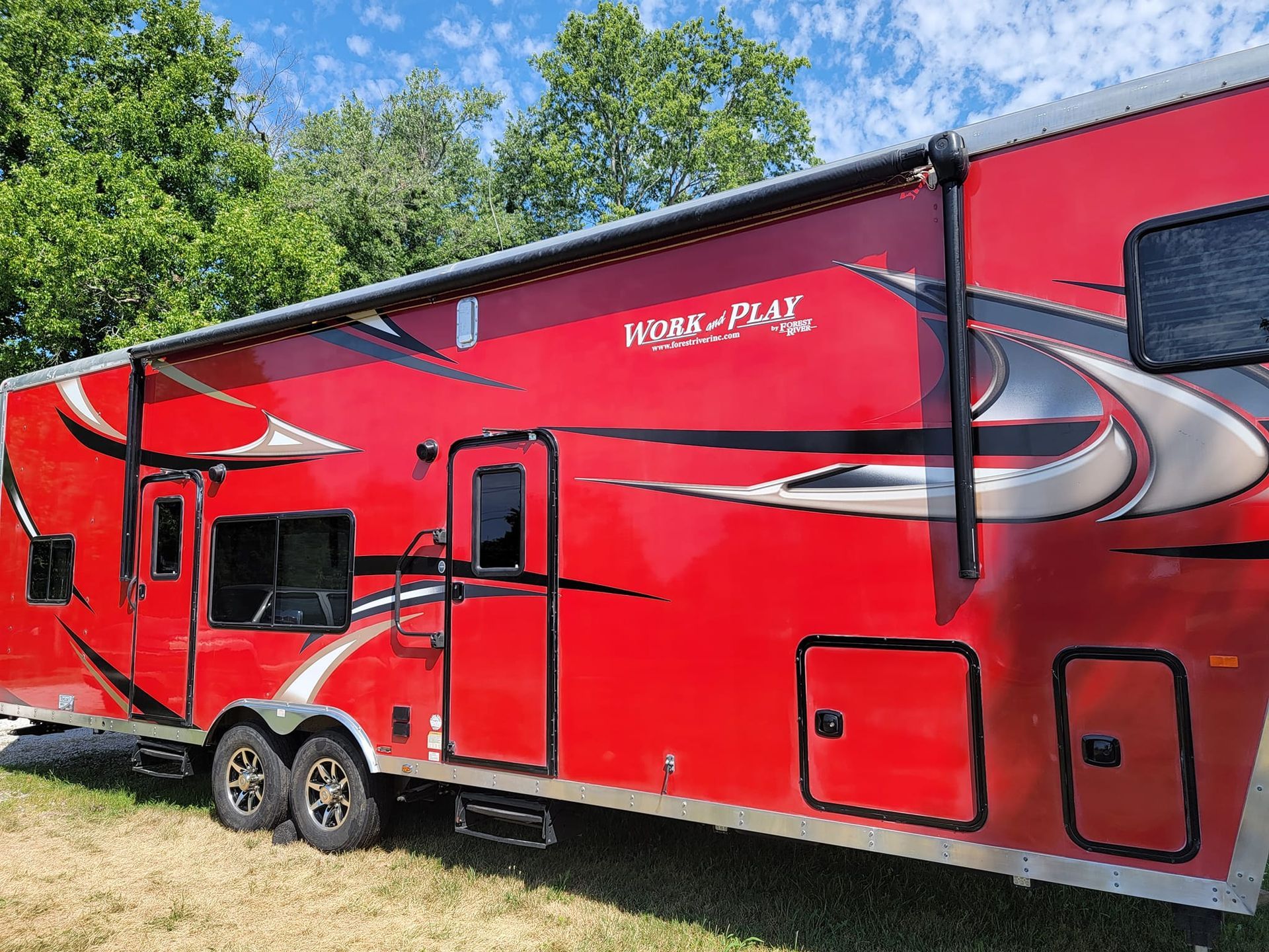 A red trailer is parked in a grassy field.
