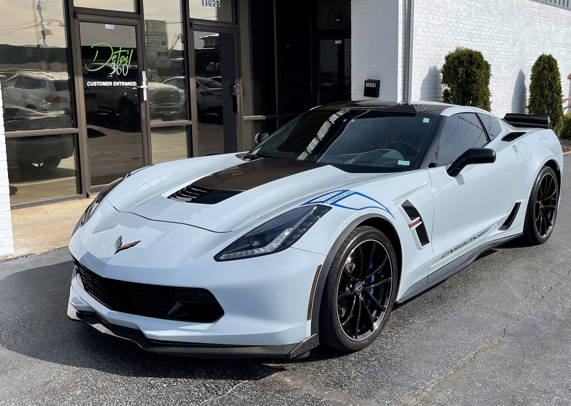 A white corvette zr1 is parked in front of a building.