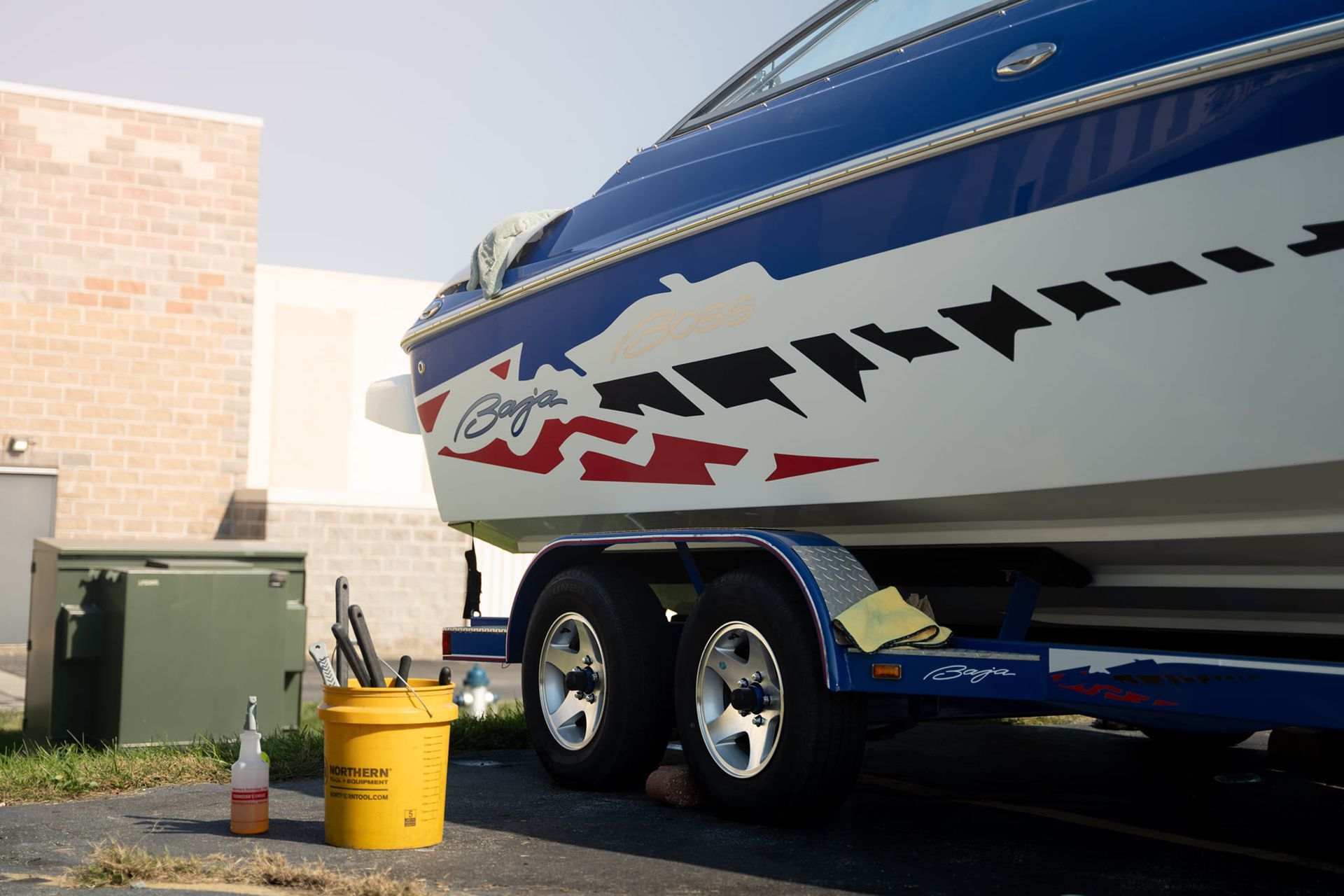 A green and white boat is parked in a parking lot.