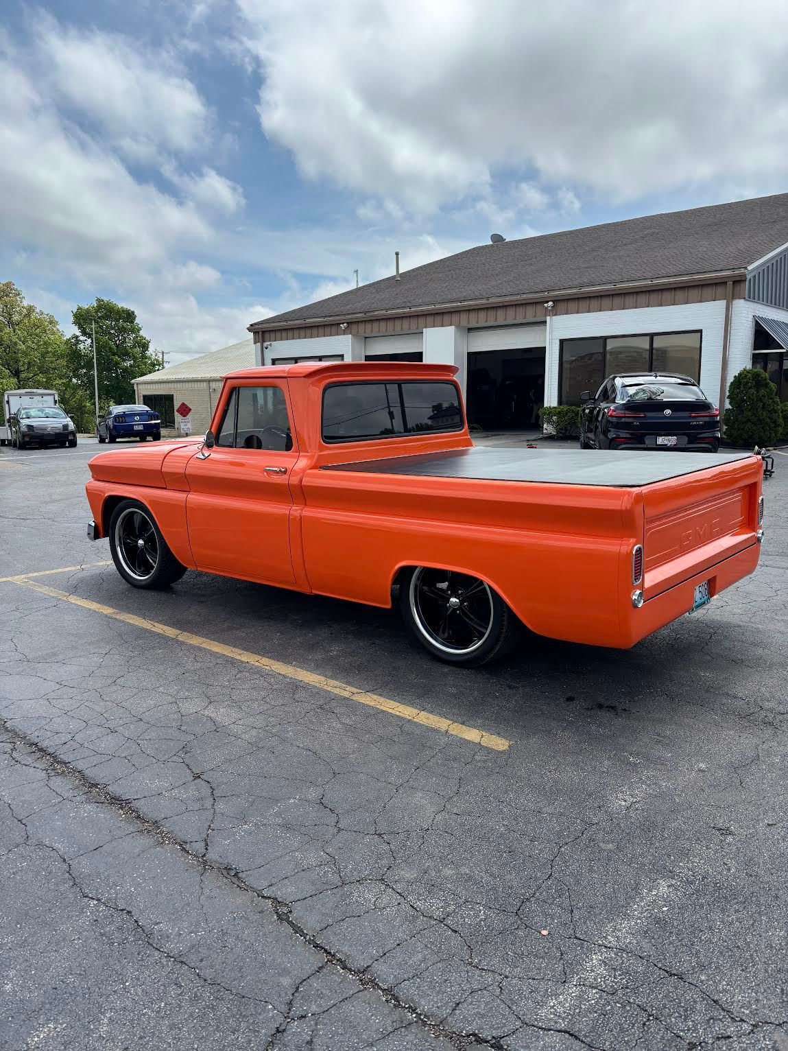 Orange Chevrolet pickup truck parked in a lot, lowered with black wheels.