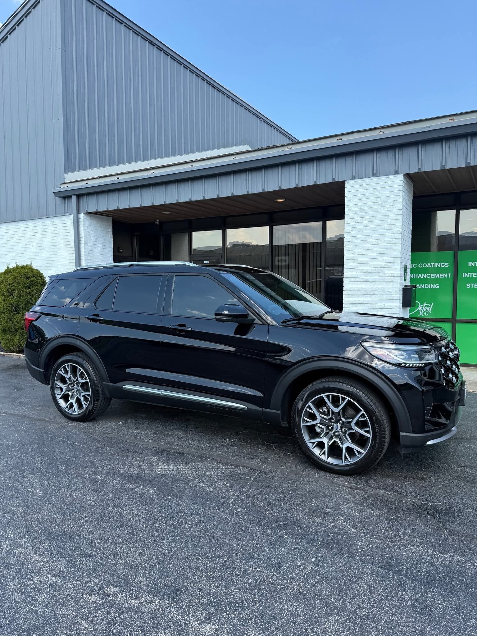 Black Ford Explorer SUV parked in front of a building with a light blue sky in the background.