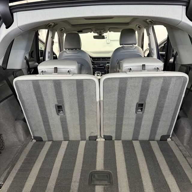 Rear view of the trunk and back seats of a car, folded down, with striped gray carpet and upholstery.