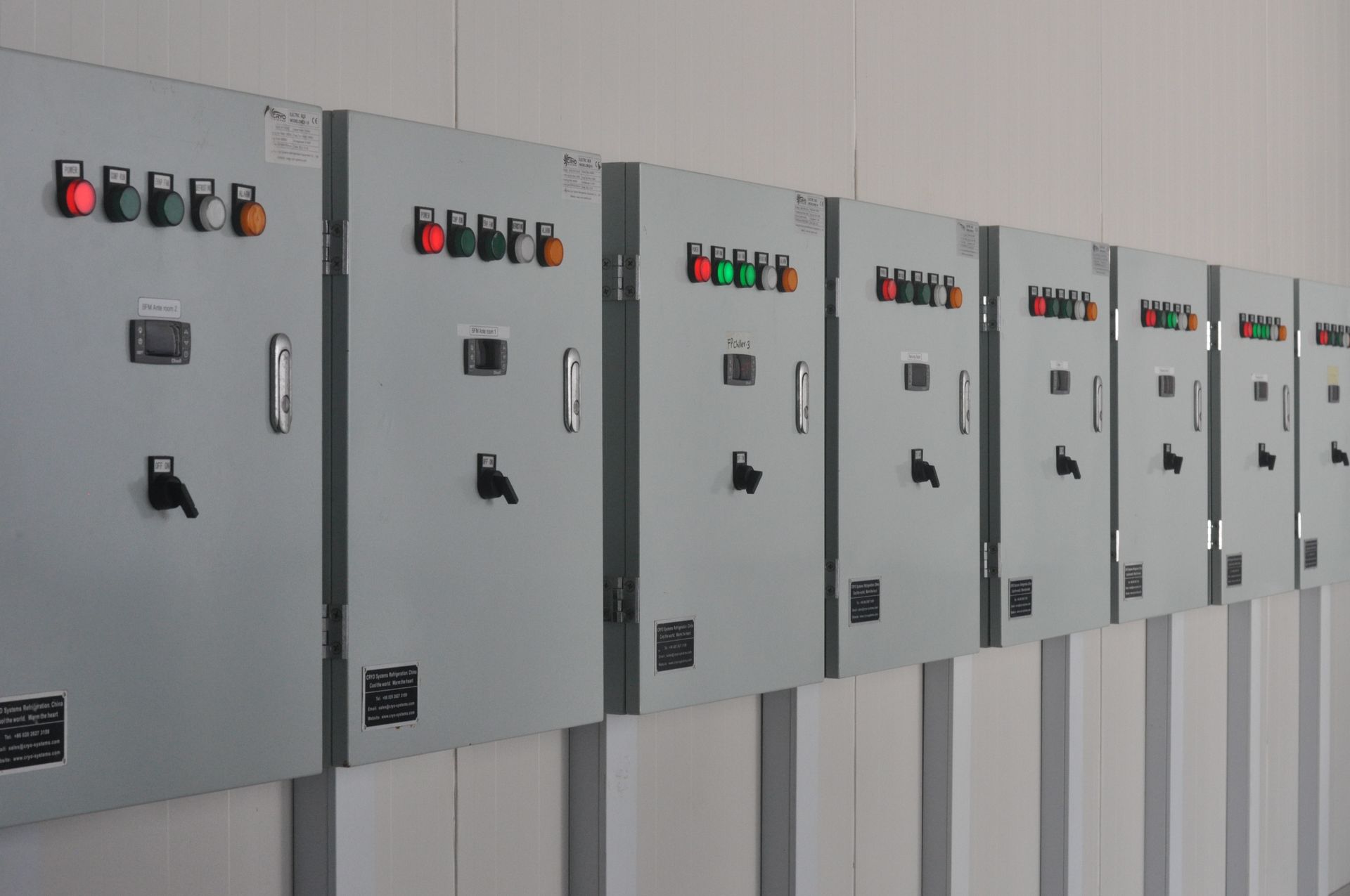 A row of electrical boxes are lined up on a wall.