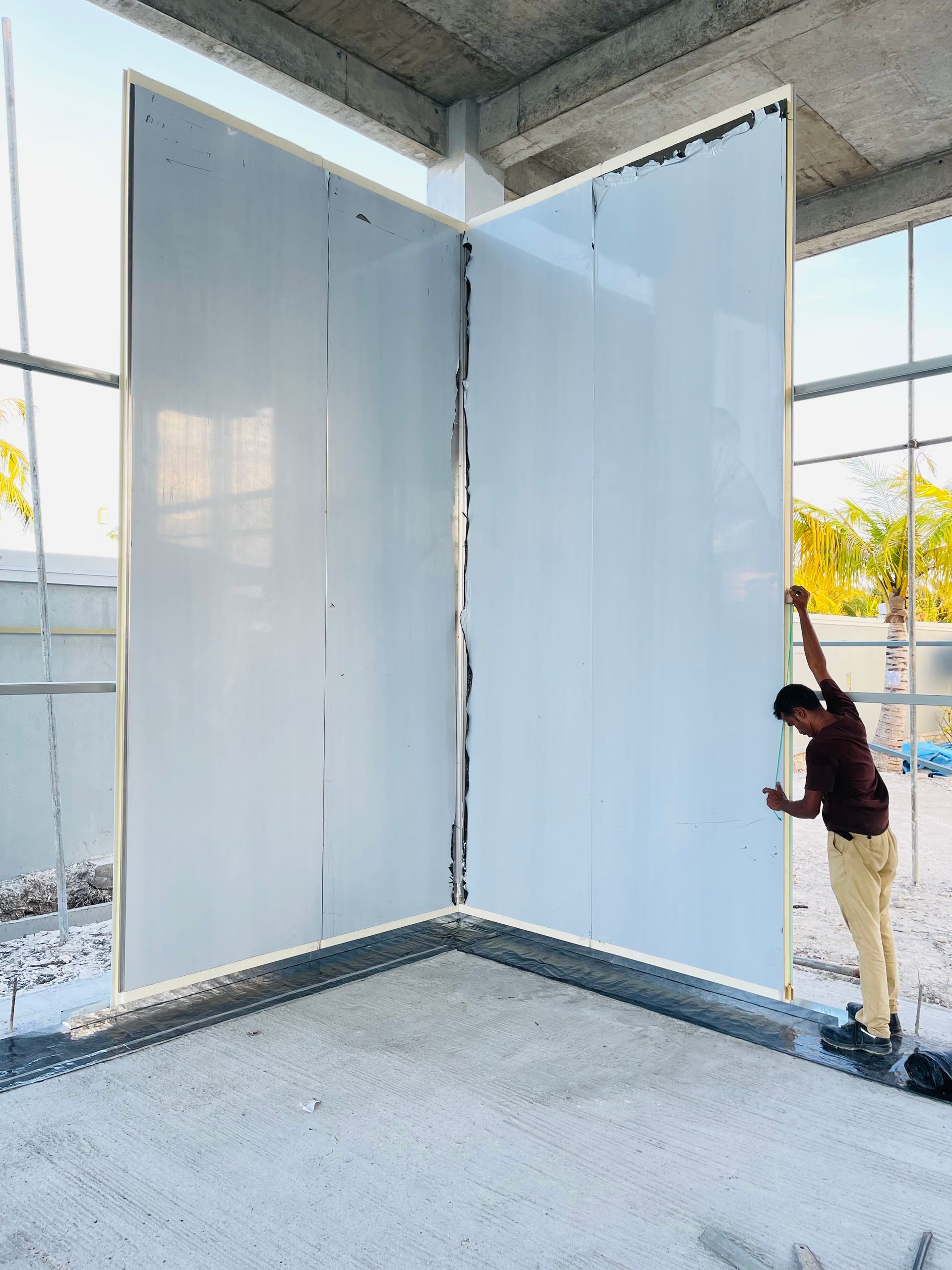 A man is standing in a room with a large white wall.
